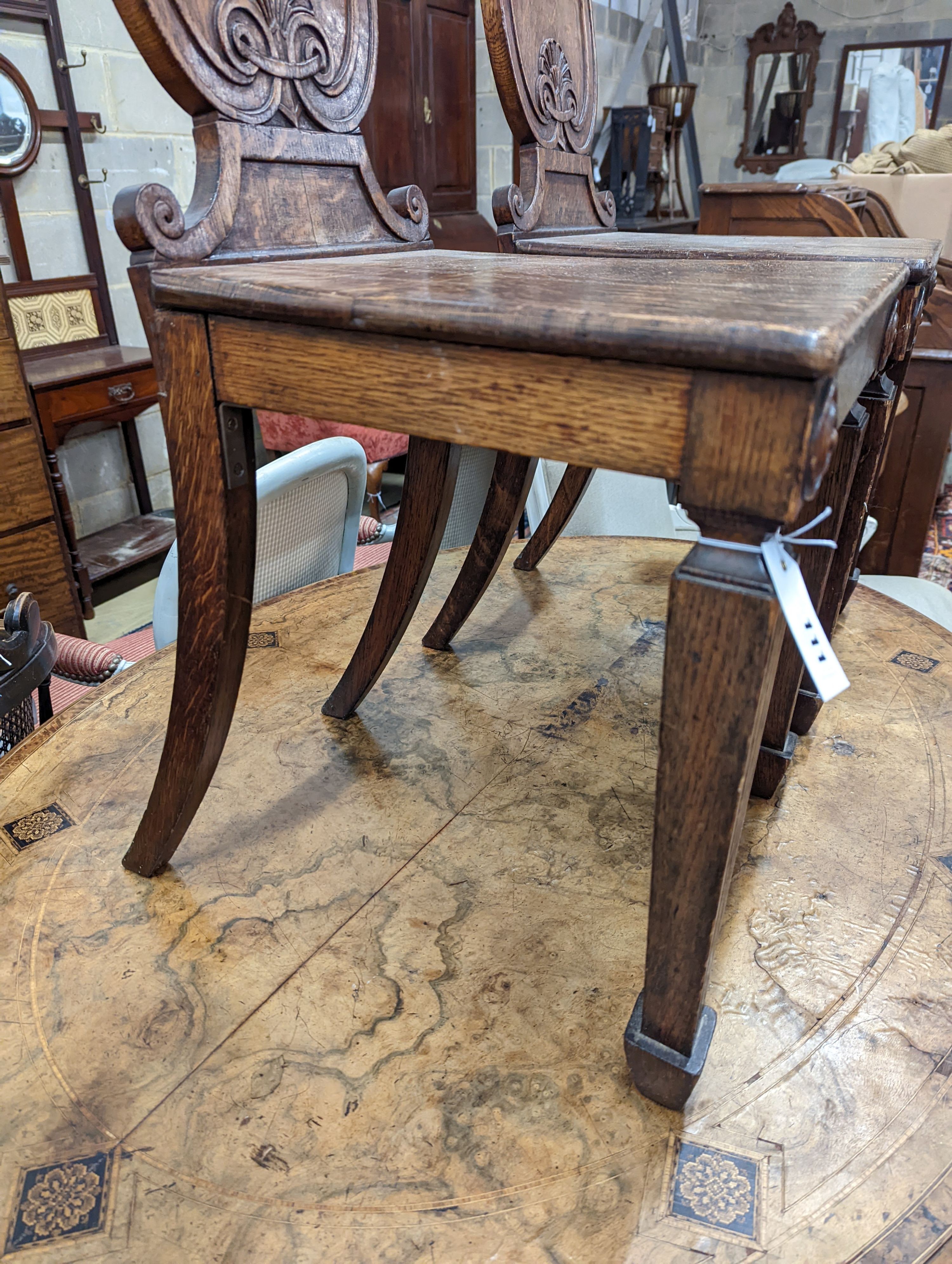 A pair of Victorian oak hall chairs with painted armorials, width 43cm, depth 39cm, height 94cm